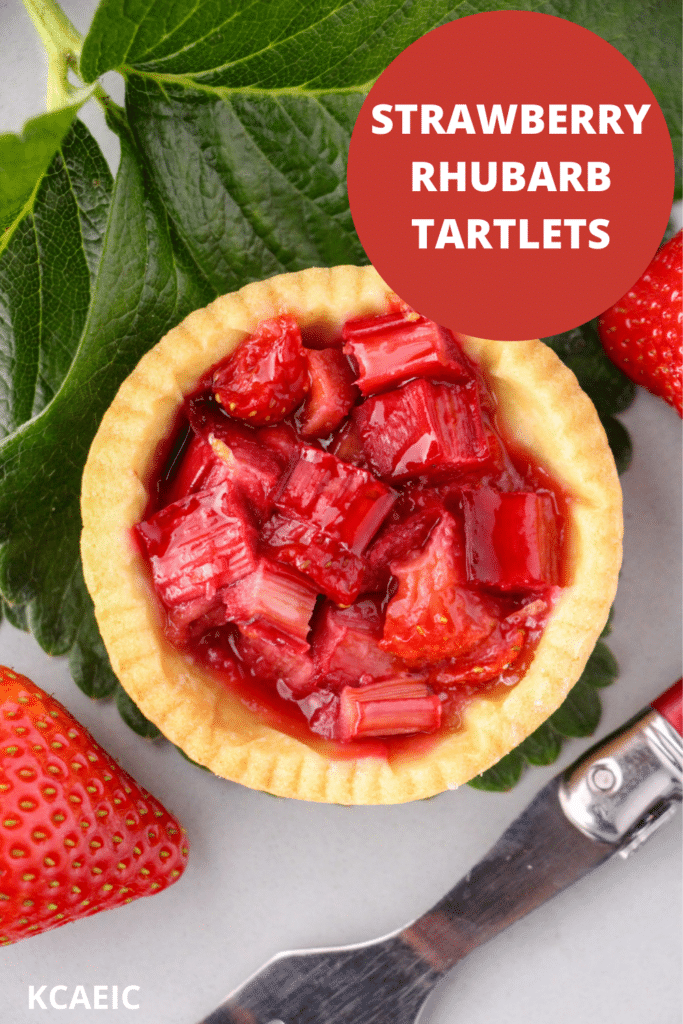 Close up strawberry rhubarb tartlets with strawberry leaves and fresh strawberries and a vintage cake fork on the side, with text overlay, strawberry rhubarb tartlets and KCAEIC.