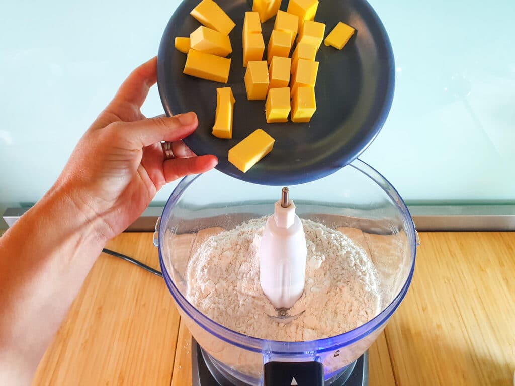 Adding cubed butter to food processor.