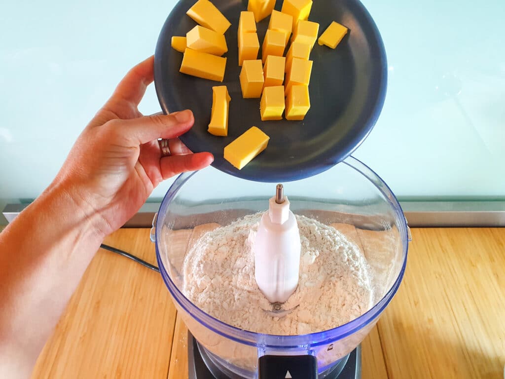 Adding cubed butter to food processor.
