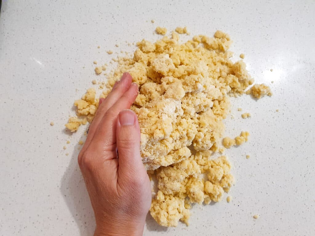 Pushing together dough with hands to form a disk.