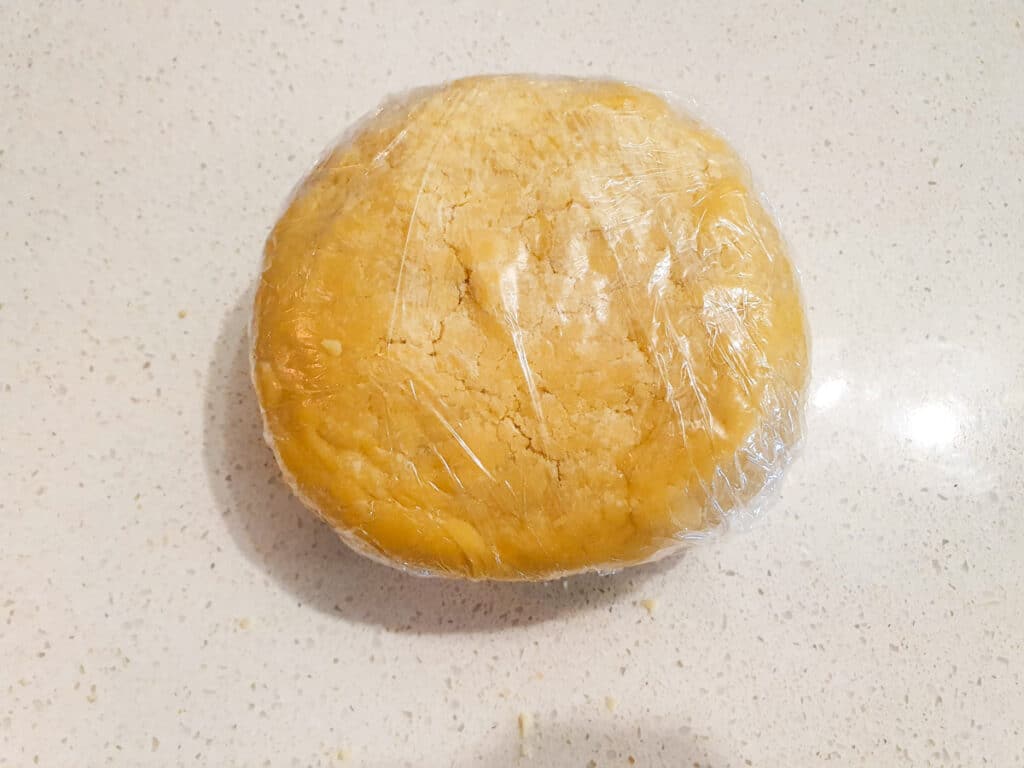 Pastry dough in disk shape that's been firmly wrapped in cling film.