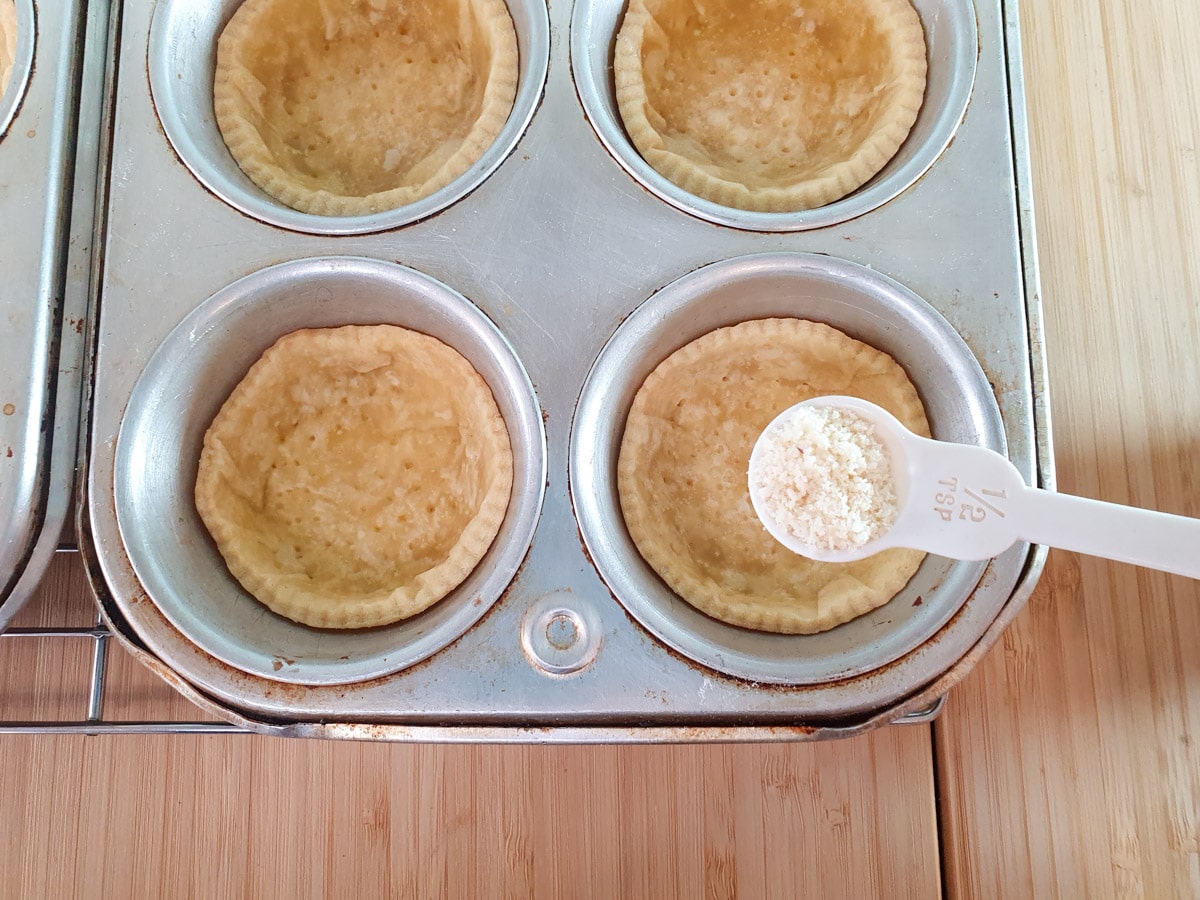 Adding almond flour to tartlet cases.