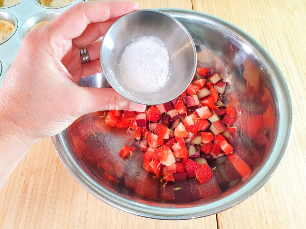 Sprinkling tapioca starch over fruit mix.