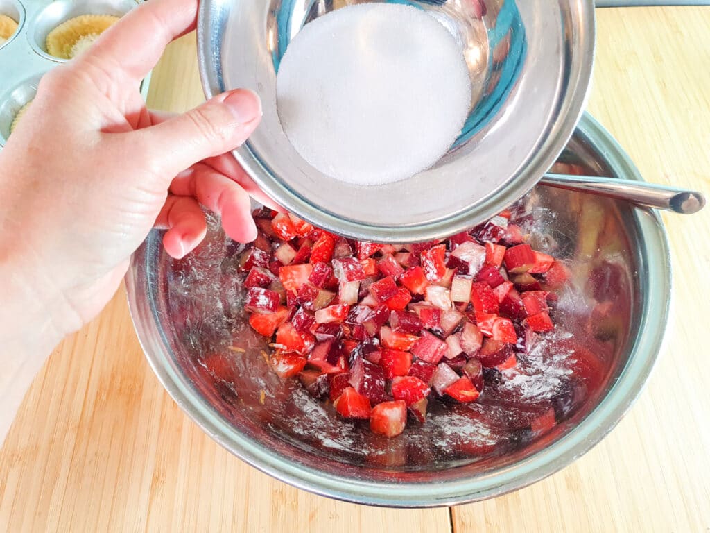 Adding sugar to fruit mix.