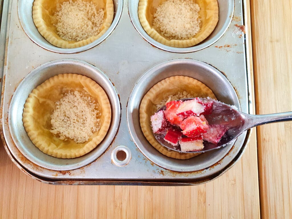 Filling tart cases with fruit mix.
