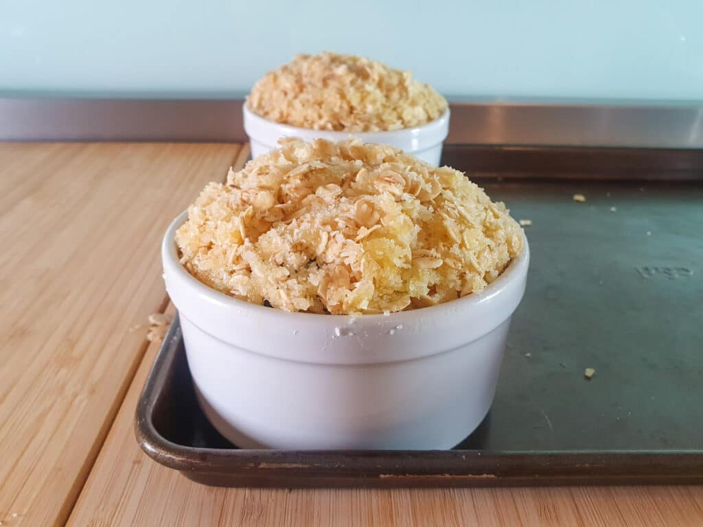 Apple and plum crumble 12 Adding crumble topping to ramakins.