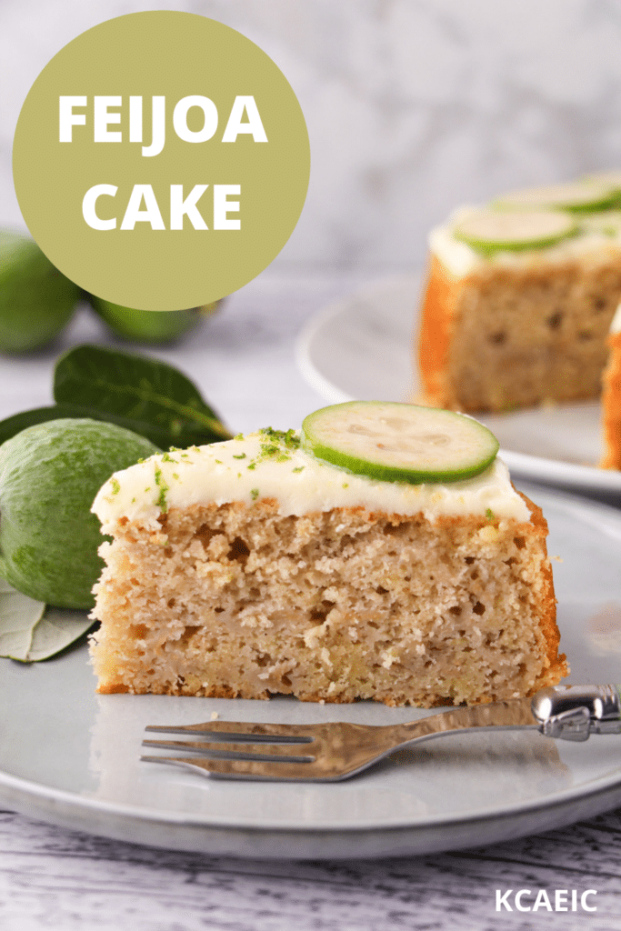 Slice of feijoa cake on a plate with a cake fork, the rest of the cake and fresh feijoas and leaves in the background, with text overlay, feijoa cake and KCAEIC.