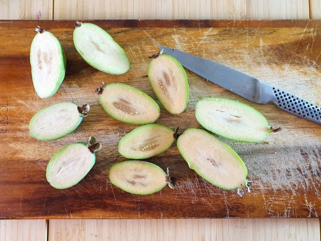 Slicing open feijoas to scoop out flesh.