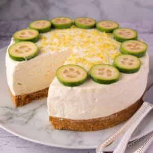 Close up feijoa cheesecake with slice taking out and silver serving ware.