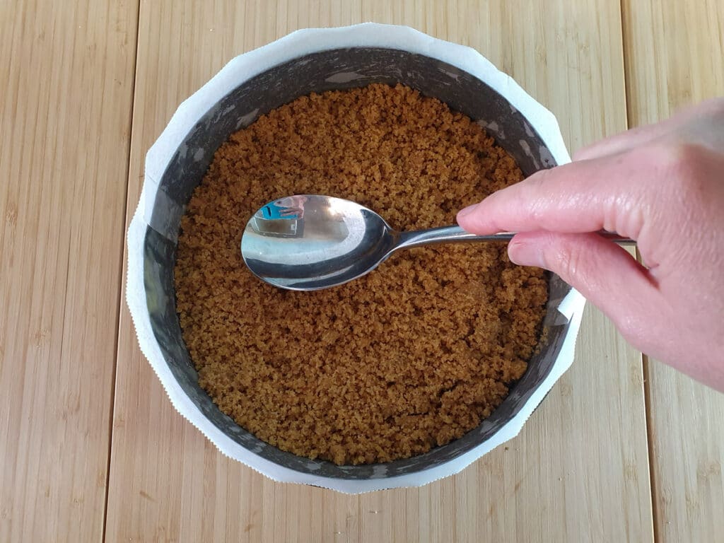 Feijoa cheesecake 6 Firming down biscuit and butter mix into pan for cheesecake base.