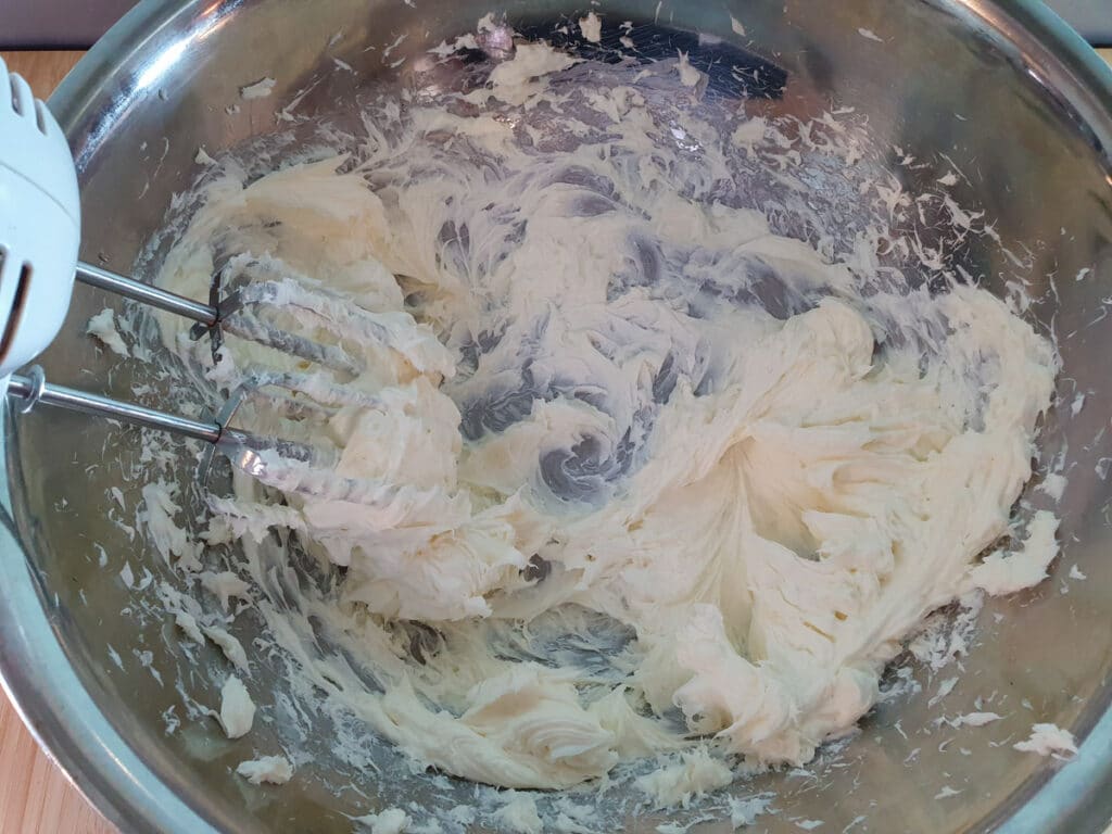 Beating cream cheese, sugar and lemon juice with a hand held electric mixer.