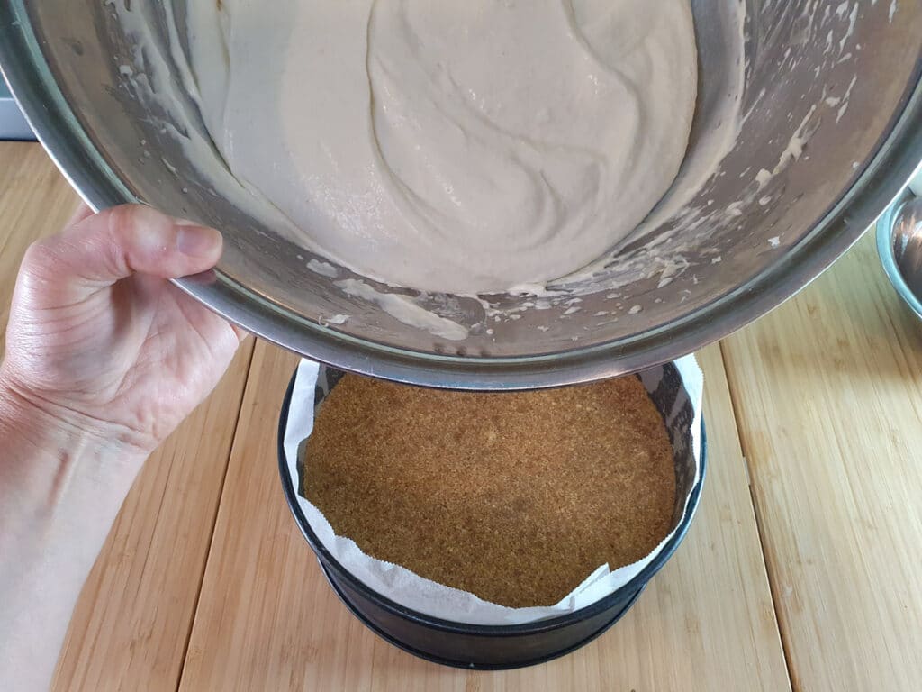 Adding cheesecake filling to base.