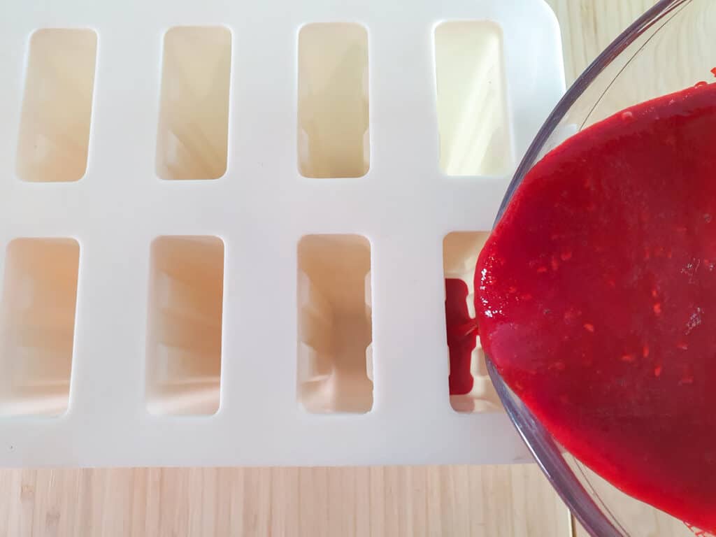 Pouring popsicle mix into molds.