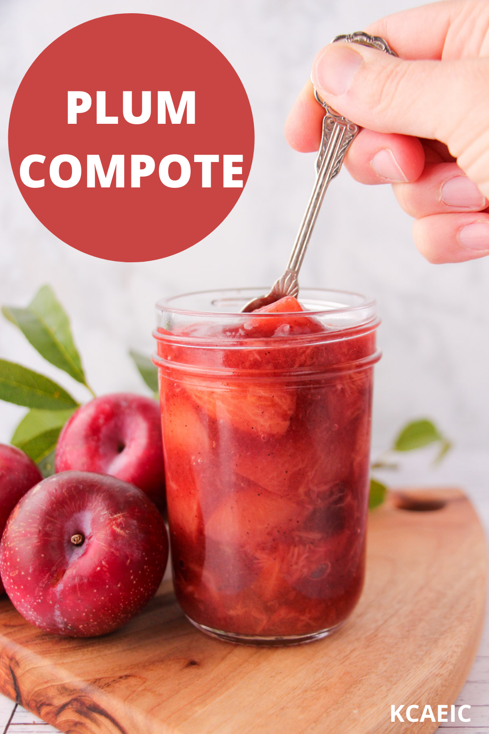 Plum compote 12 Mason jar of plum compote with a spoon being held over it, fresh plums and leave on the side and text overlay, plum compote, KCAEIC.