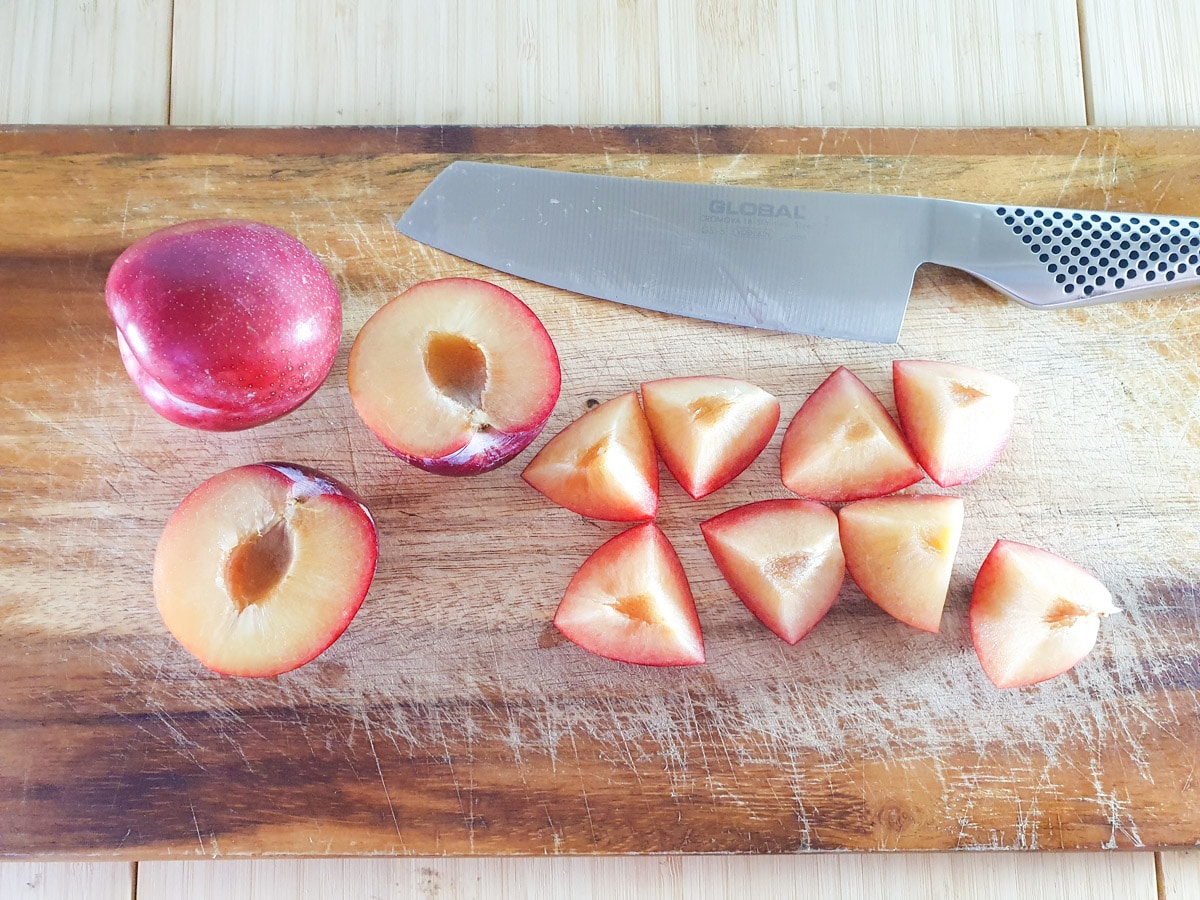 Removing stones from plums and cutting halves into quarters.