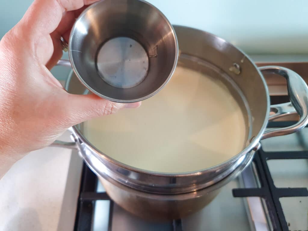 Adding glucose syrup to ice cream mix on stove.