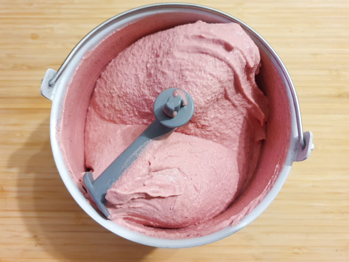 Churned ice cream in churning bowl on a chopping board.