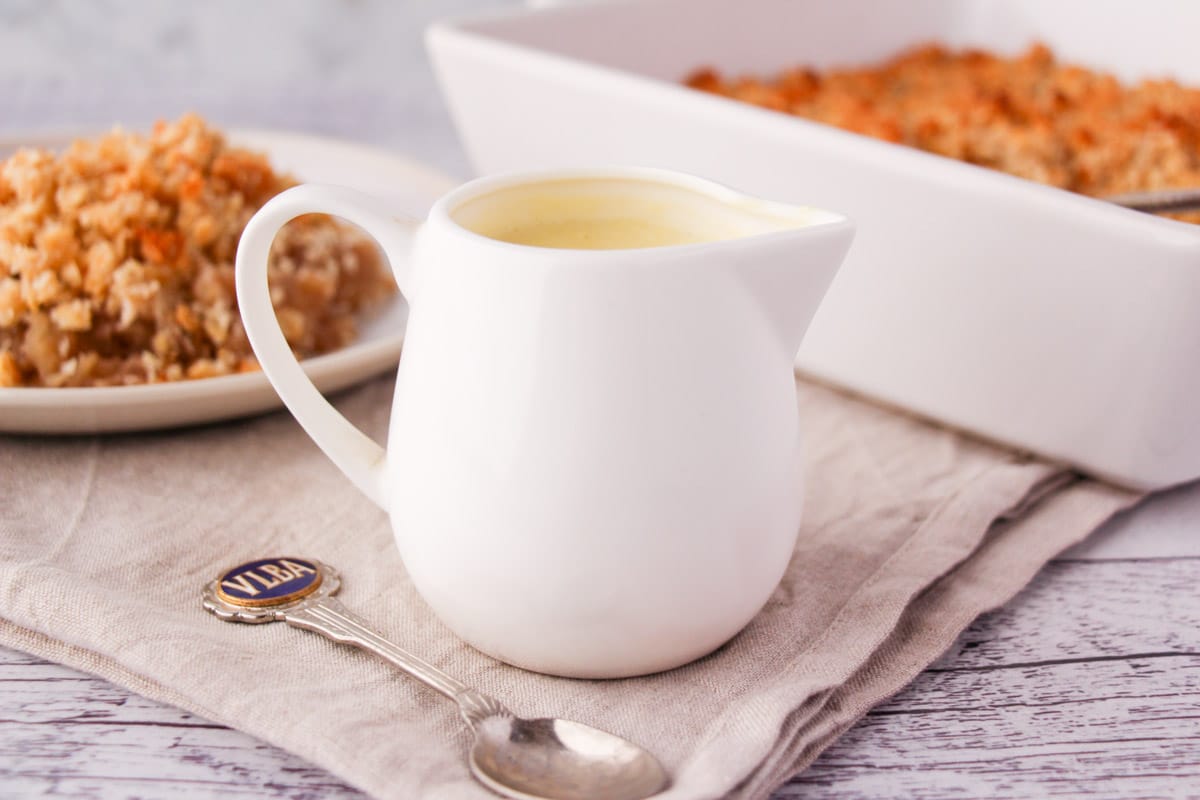 Vegan Custard 3 Jug of vegan custard with a vintage spoon and vegan apple crumble in the background.