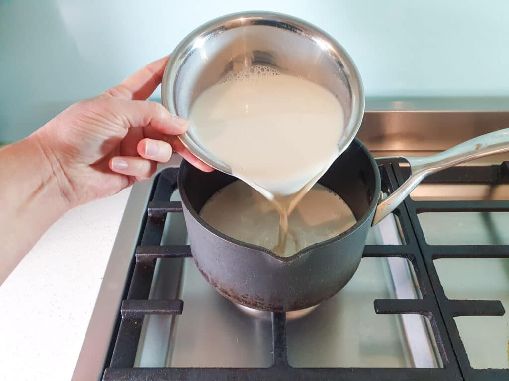 Adding soy milk to pot.