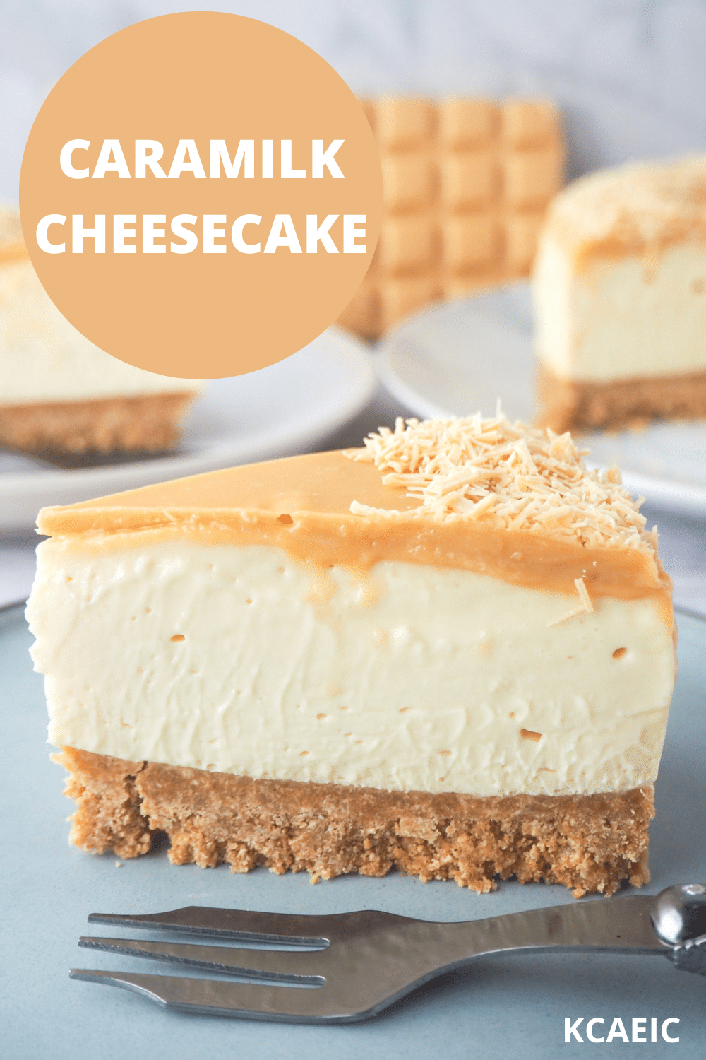 Slice of caramilk cheesecake on a plate with a fork, rest of cake, extra slice of cake and caramilk chocolate in the background, and text overlay, caramilk cheesecake, KCAEIC.