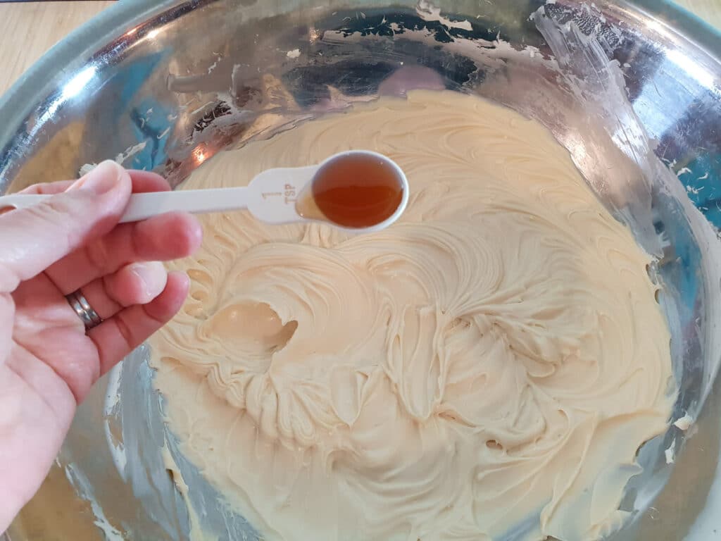 Adding vanilla extract to cheesecake filling.