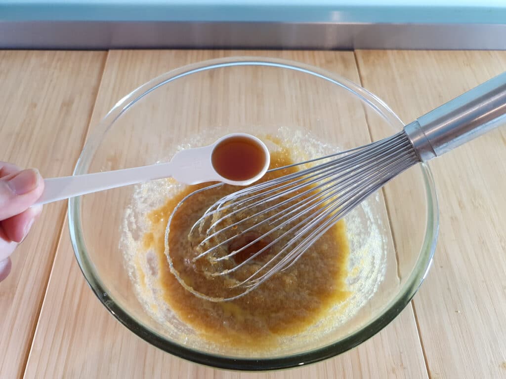 Adding vanilla extract to melted butter and sugar mix.