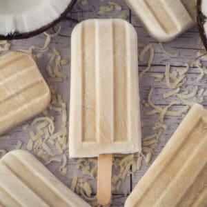 Close up coconut popsicles with fresh coconut and shredded coconut.