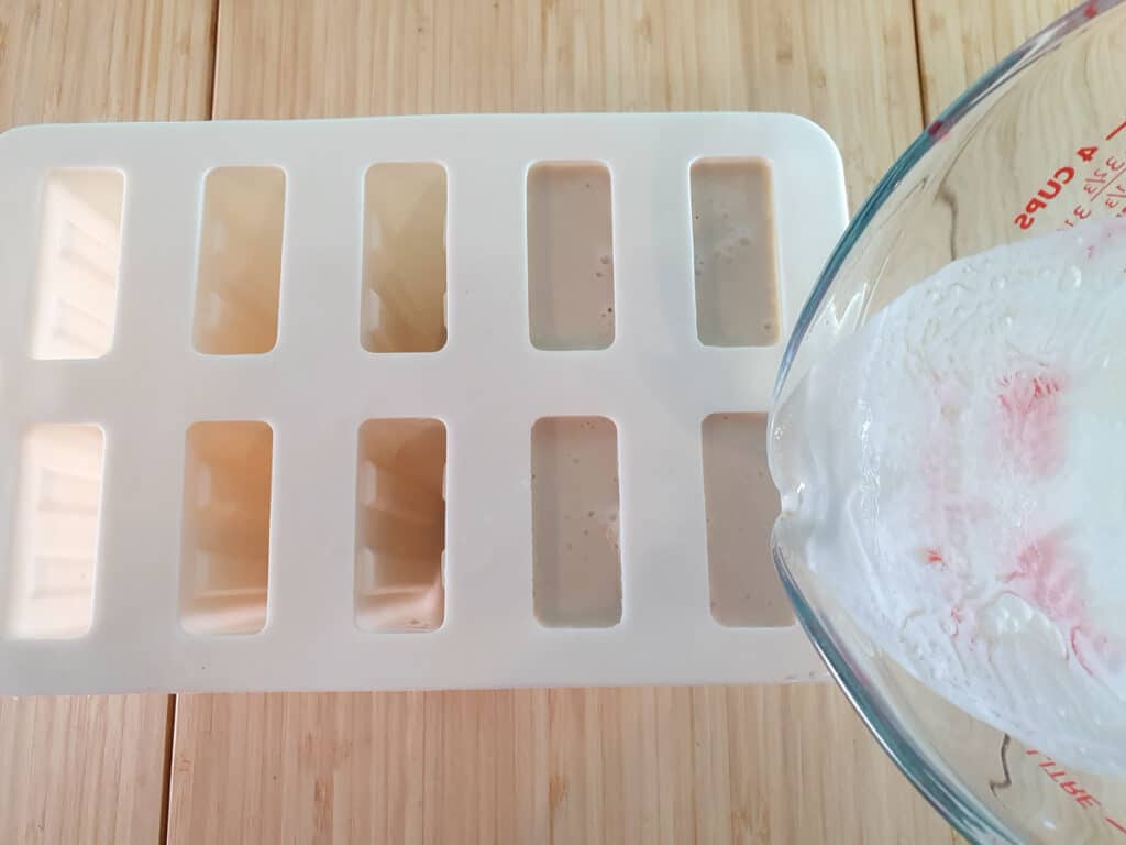 Pouring popsicle mix into popsicle molds.