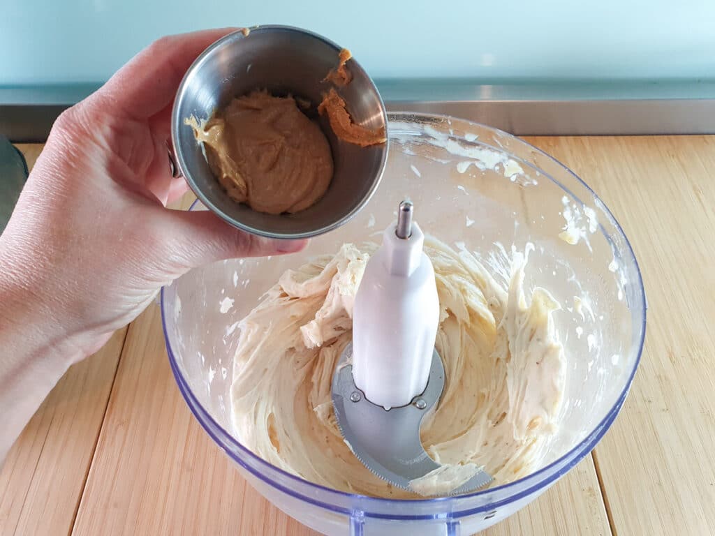 Adding cashew butter to blended bananas.