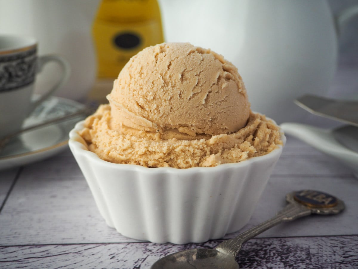 Earl grey ice cream with spoon, tea strainer and cup of tea in the background.