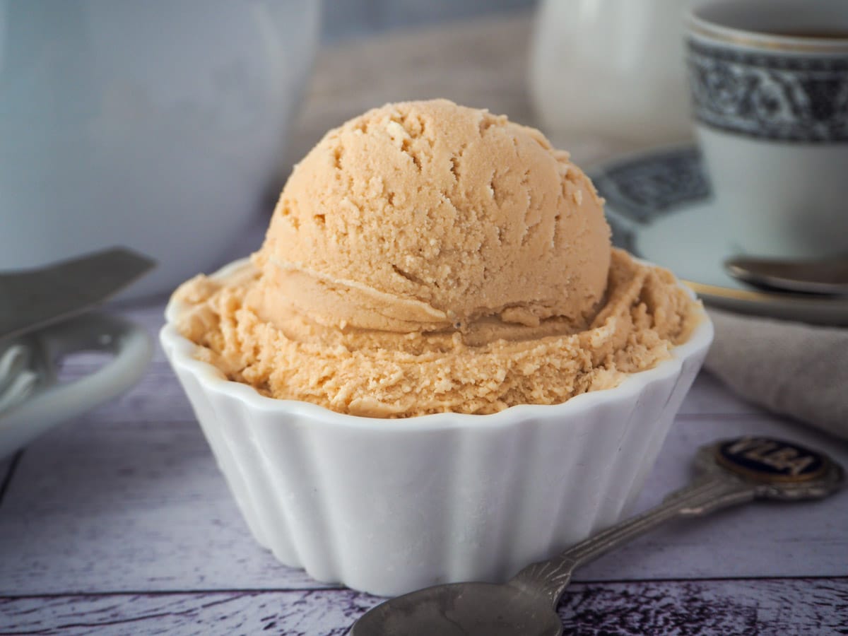 Earl grey ice cream with spoon and tea strainer and cup of tea in the background.