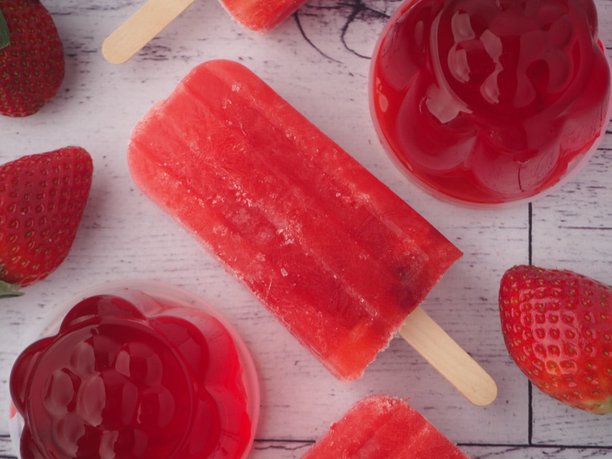 Strawberry jello popsicle with mini strawberry jello molds and fresh strawberries.