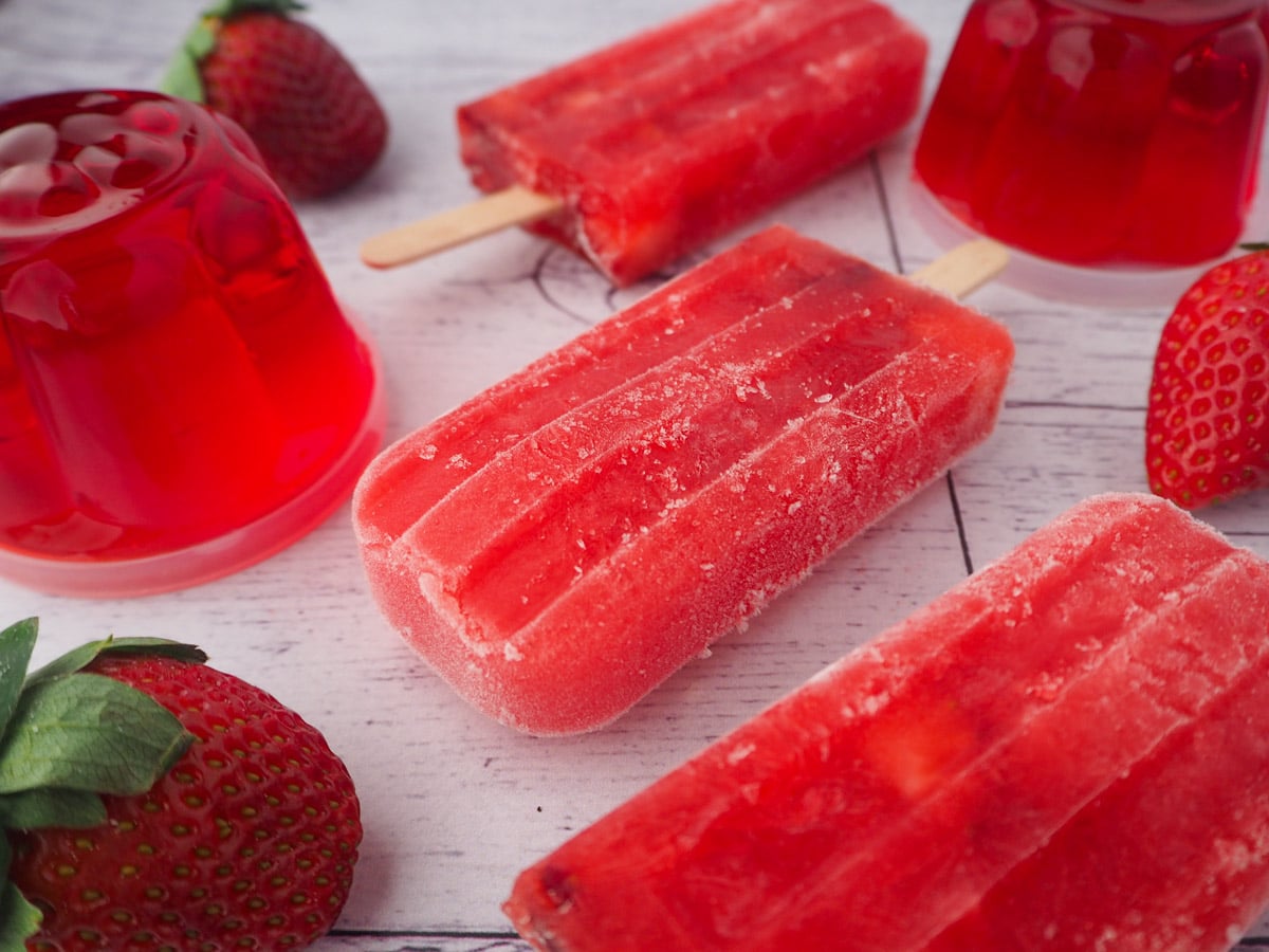 Strawberry jello popsicle with mini strawberry jello molds and fresh strawberries.