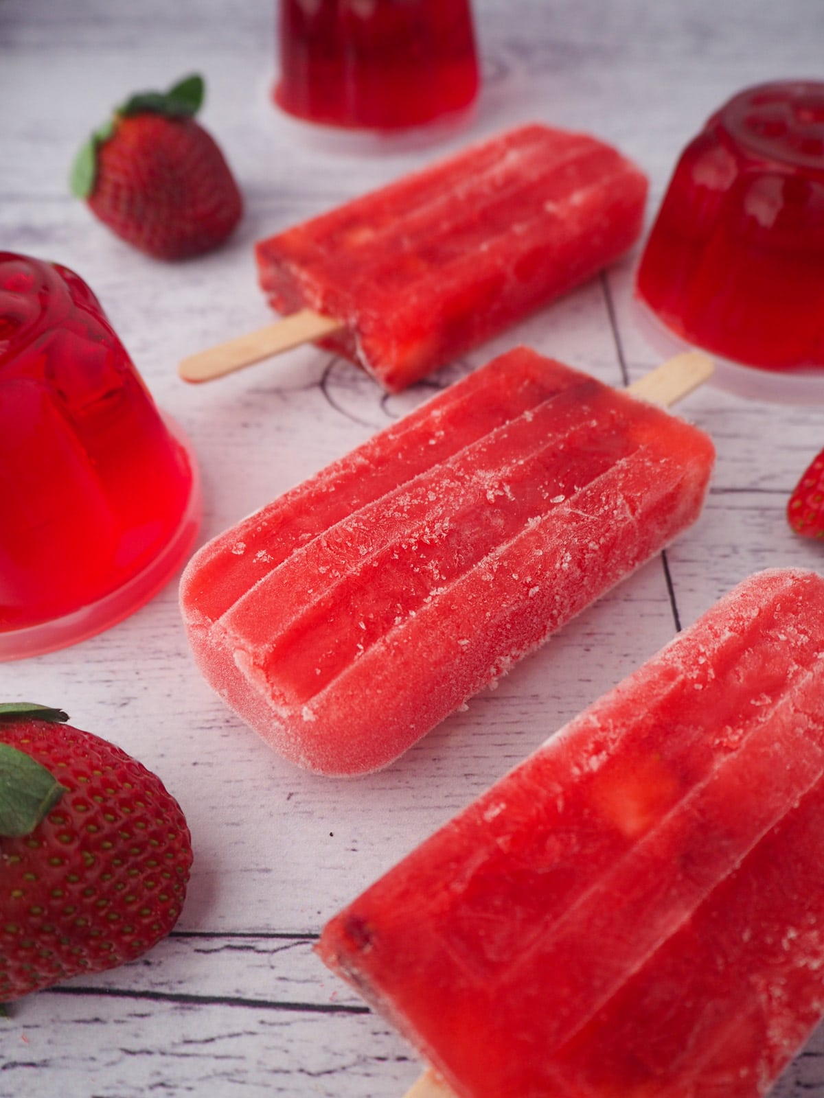 Strawberry jello popsicles with mini molded strawberry jellos and fresh strawberries.