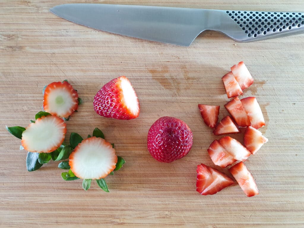 Jello popsicles 7 Chopping up strawberries into bite sized pieces.