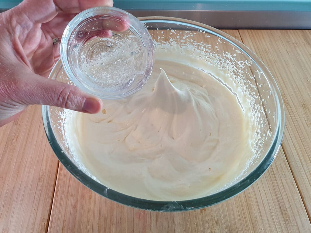 Adding melted glucose syrup to whipped cream.