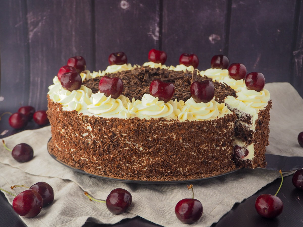 Taking out of slice of cake, with fresh cherries.