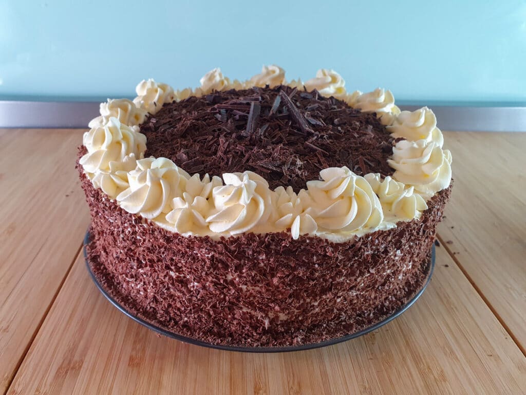 Traditional Black Forest Cake 35 Adding chopped chocolate to top of cake.