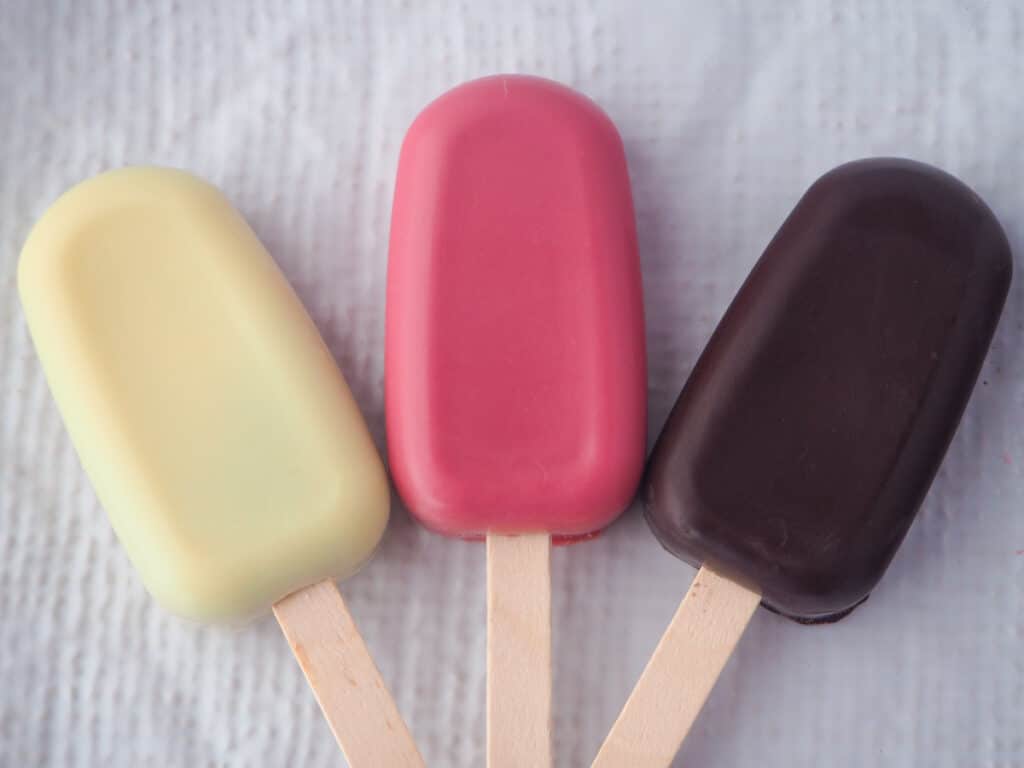 Undecorated cake pops in three different colours, white chocolate, ruby chocolate and dark chocolate.