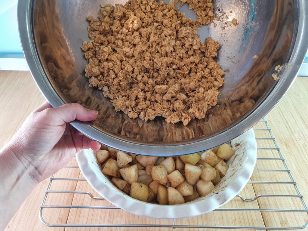 Adding crumble topping to baked pears.