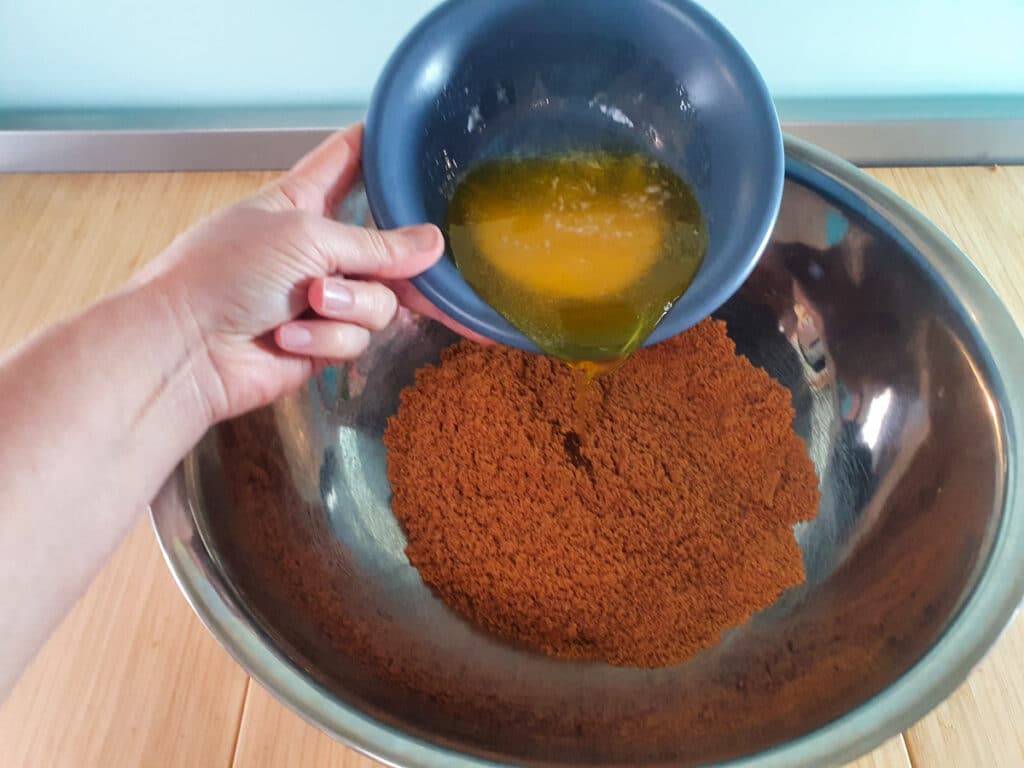 Adding melted butter to cookie crumbs.