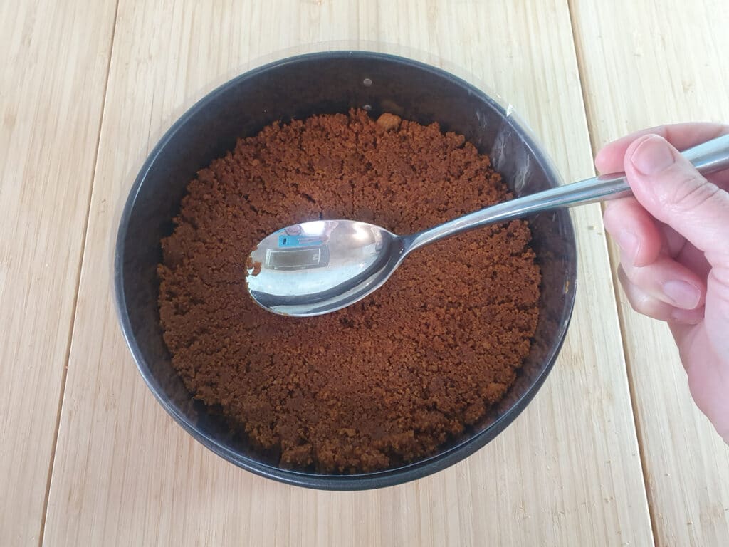 Pressing down cookie and butter mix into the bottom of the pan.