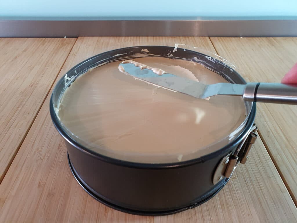 Smoothing top of cheesecake with an offset spatula.