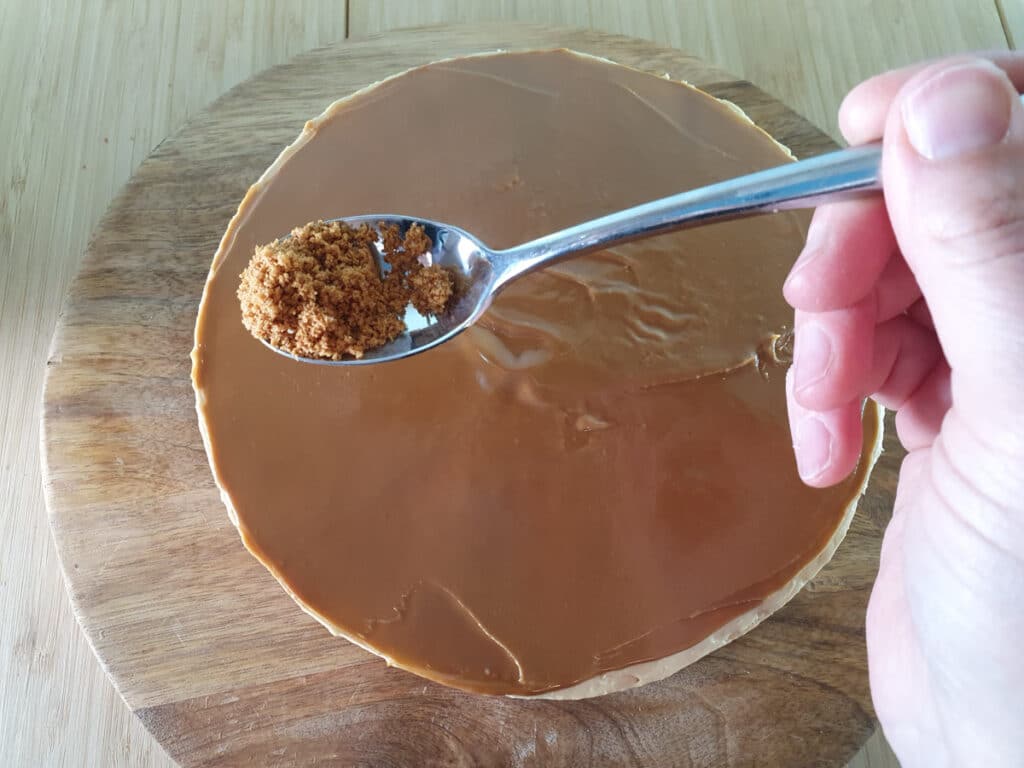 Adding cookie crumbs to the edge of the top of the cheesecake.