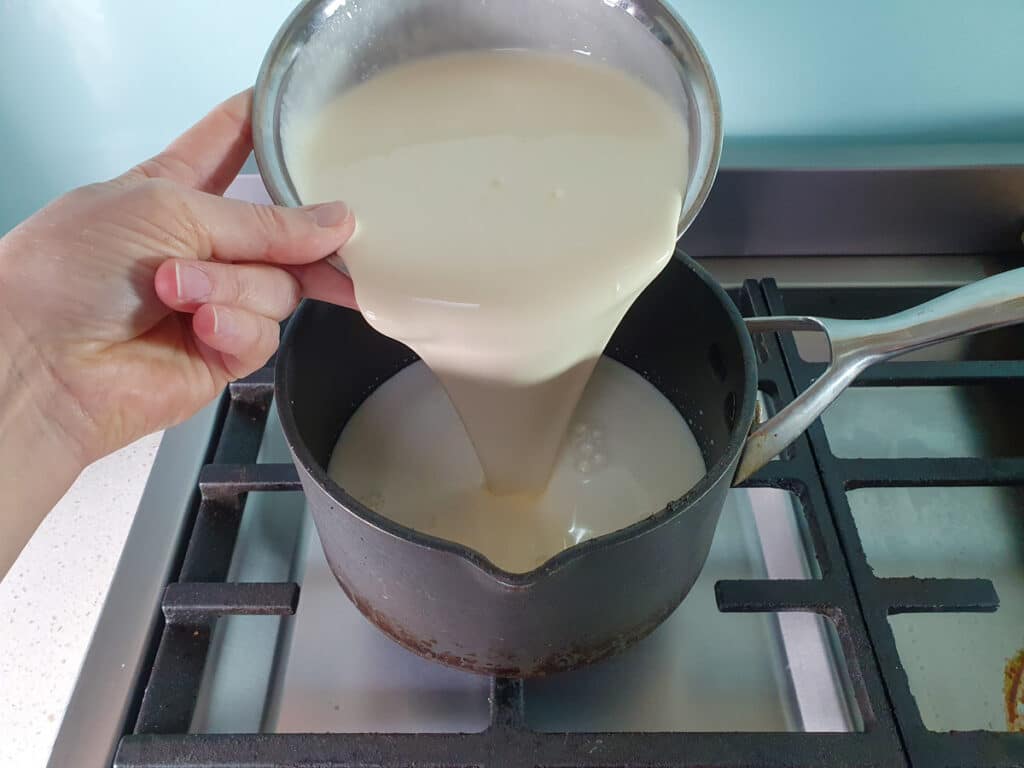 adding cream to pot on stove top.