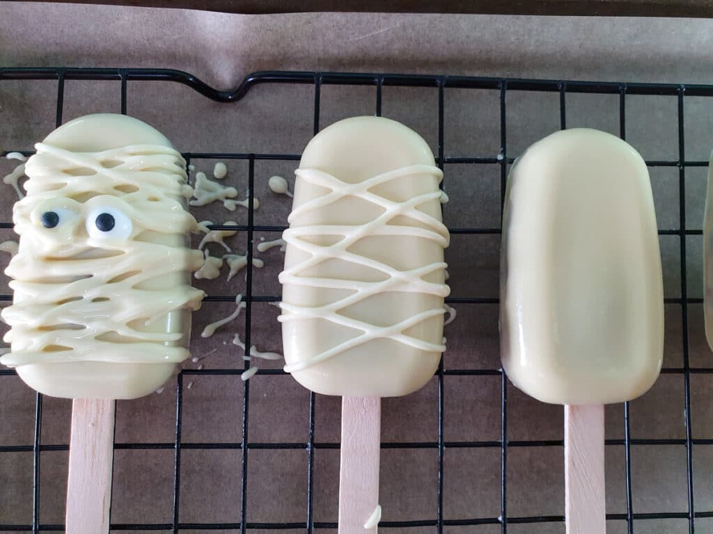 Halloween cakesicles 32 Drizzling a few lines of chocolate on first, then sticking on eyes.
