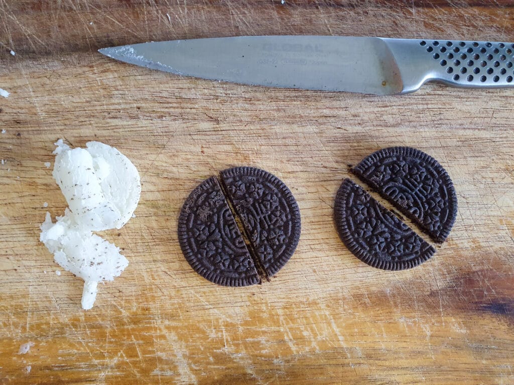 Halloween cakesicles 21 Scraping off cream and cutting Oreos in half.