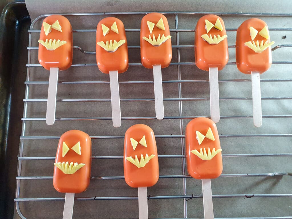 Sticking jack-o-lantern decorations onto cakesicles.