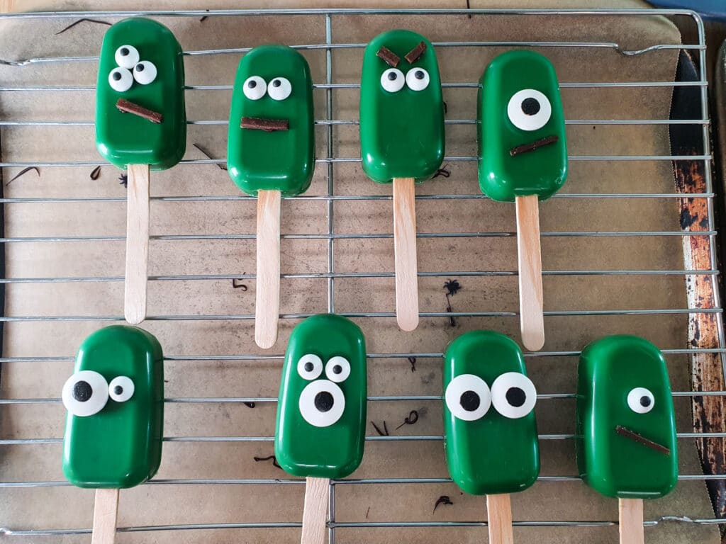 Halloween cakesicles 35 Sticking decorations onto monster cakesicles.