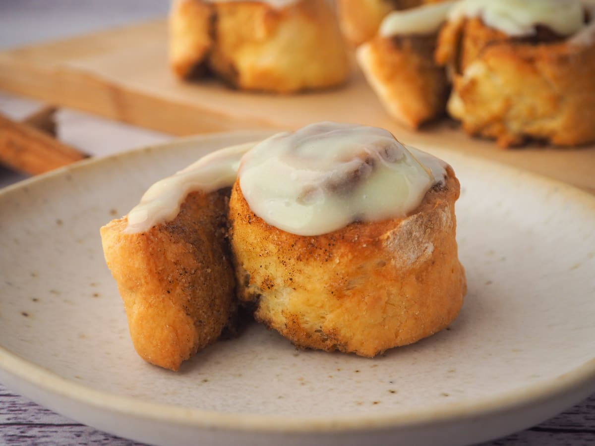 Air fryer cinnamon roll on a plate, with rolls in background.